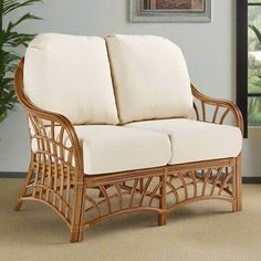 a wicker loveseat with white cushions in front of a painting on the wall