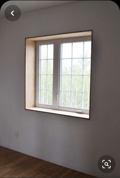 an empty room with a window and hard wood floor