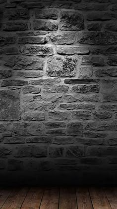 a black and white photo of a brick wall with wood flooring in the foreground