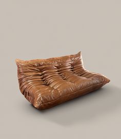 a brown leather couch sitting on top of a gray floor