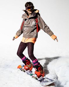 a woman riding a snowboard down a snow covered slope with skis on her feet