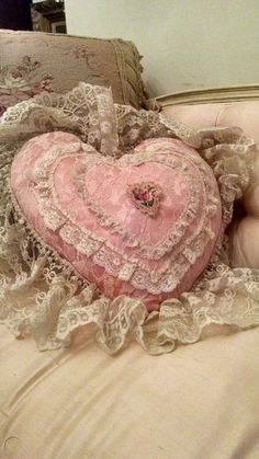 a pink heart shaped pillow sitting on top of a bed