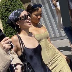 two women walking down the street with one holding a cell phone in her other hand