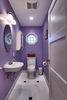 a bathroom with purple walls and flooring in the middle, along with a white toilet and sink