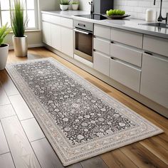 a large rug in the middle of a kitchen with white cabinets and wooden flooring