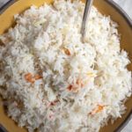 a bowl filled with rice and carrots on top of a table