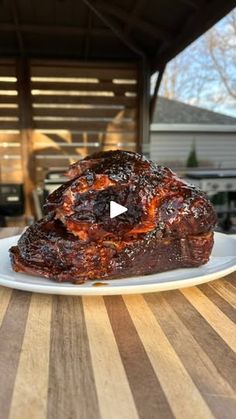 a piece of meat sitting on top of a white plate next to a wooden table