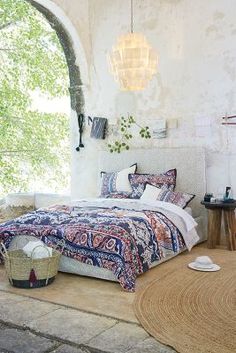 a bedroom with an arched window and colorful bedding