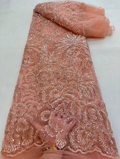 an orange and pink dress with sequins on the bottom is laying on a white surface