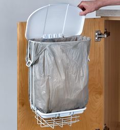 a person holding a plastic bag over a trash can