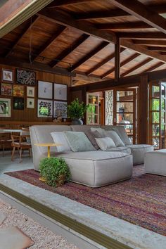 a living room filled with lots of furniture next to a wooden ceiling covered in pictures