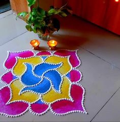 a colorful rug with candles on the floor next to it and a potted plant