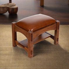 a wooden bench with a leather seat on top of it in front of a rug