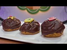 three chocolate covered donuts sitting on top of a white plate