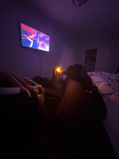 a person laying on a bed in front of a flat screen tv with the lights on