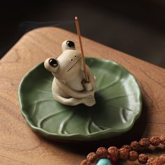 a ceramic frog incense burner on a green plate with beads and bead necklace