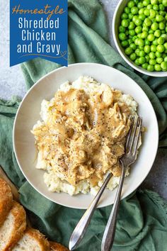 a white plate topped with mashed chicken and gravy next to green peas