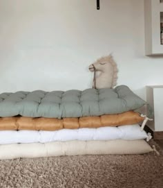 three pillows stacked on top of each other in front of a white wall and floor