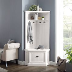 a white coat rack sitting in the corner of a room next to a chair and potted plant