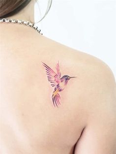 the back of a woman's shoulder with a hummingbird tattoo on it