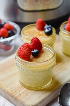 small jars filled with pudding and berries on a cutting board