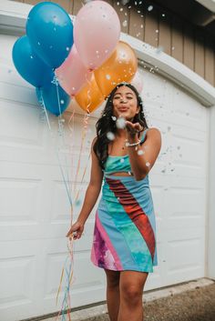 a woman standing in front of a garage while holding onto balloons and confetti