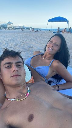 a man laying on top of a woman in a blue bathing suit at the beach