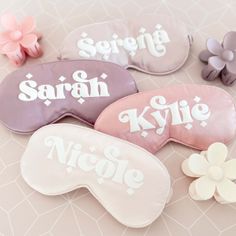 three sleep masks with names on them sitting on a table next to flowers and leaves