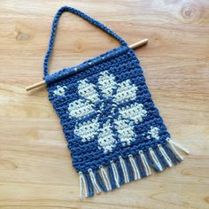 a crocheted blue and white bag sitting on top of a wooden table next to a knitting needle