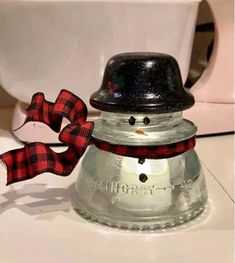 a metal bell with a red and black bow on it sitting next to a toilet