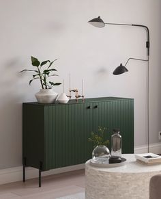 a living room with a green cabinet and potted plants