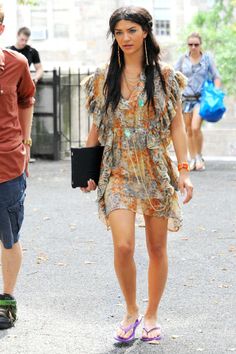 a woman walking down the street with a skateboard in her hand and another man standing behind her