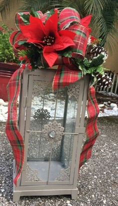 a lighted lantern decorated with poinsettias and greenery for the holiday season