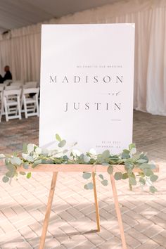 a sign that says madison and just in front of some chairs with greenery on them