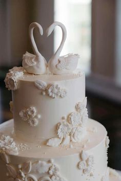 a white wedding cake with swans on top