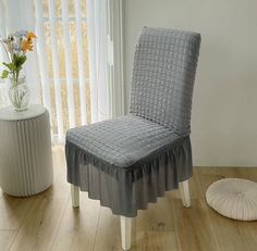 a gray chair with a pleated cover on it in front of a white window