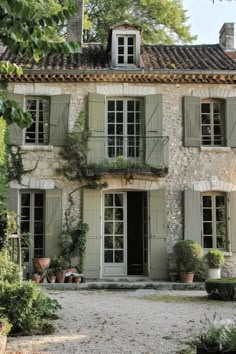 an old stone house with green shutters and potted plants