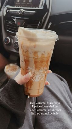 a person holding up a cup of iced caramel macchiato in their hand