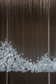 an abstract sculpture made out of ice cubes in front of a brown wall with vertical lines