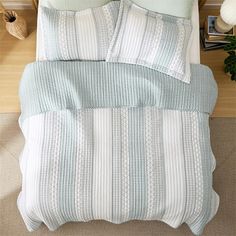 an overhead view of a bed with blue and white comforter, pillows and blankets