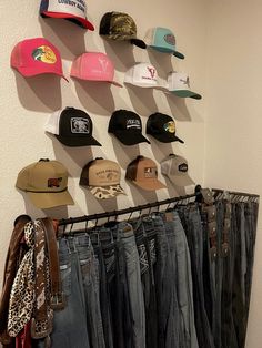 several hats are hanging on the wall next to some jeans and jacket hangers in front of them