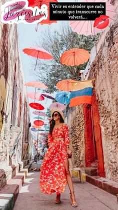 a woman in a red dress is walking down the street with many colorful umbrellas