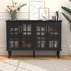 a black cabinet with glass doors and gold trimmings in front of a white wall