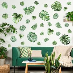 a living room filled with furniture and lots of green leaves on the wall behind it