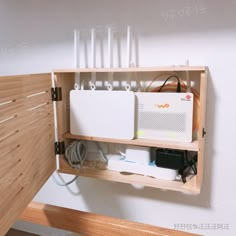 a wooden shelf with electronic equipment and wires attached to the wall above it in a room