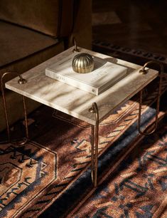 a coffee table with a book on it and a golden ball sitting on top of it