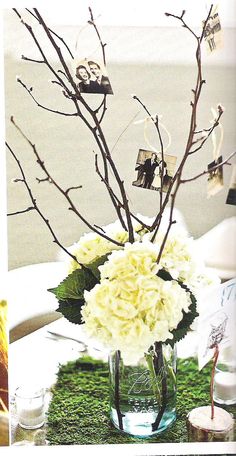 a vase filled with white flowers sitting on top of a green moss covered tablecloth