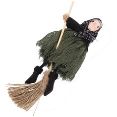 a doll is hanging on a rope with a broom in its hand and wearing a green dress