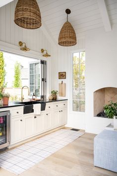 a kitchen with white cabinets and black counter tops, an oven in the corner and potted plants on the window sill