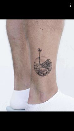 a man's foot with a small tattoo on the ankle and palm tree in the middle